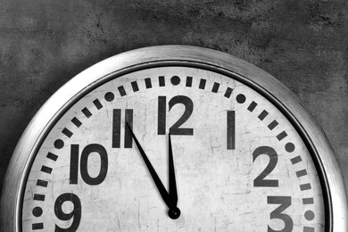 Photo of Stylish analog clock hanging on grey wall. New Year countdown