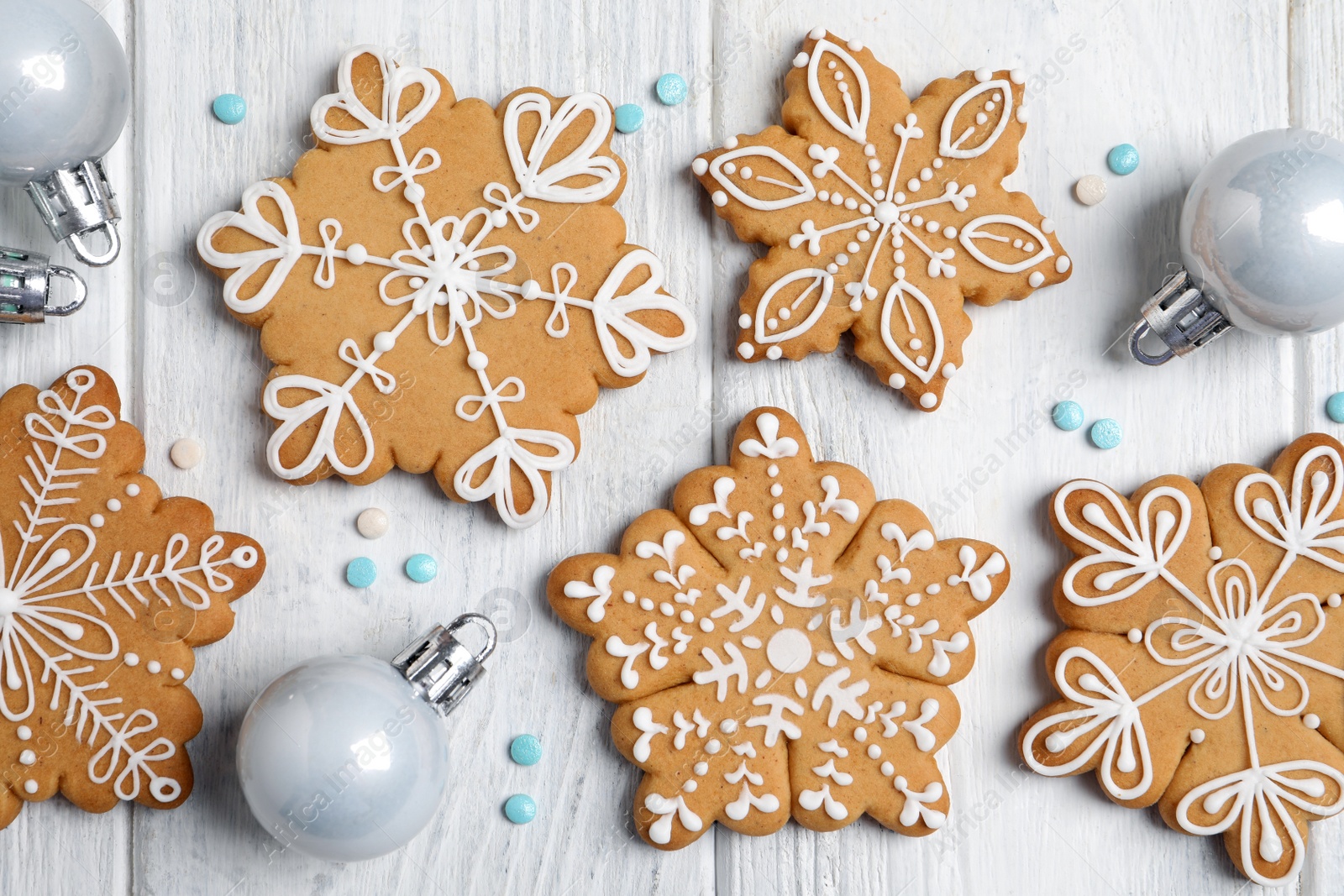 Photo of Tasty Christmas cookies and baubles on white wooden table, flat lay
