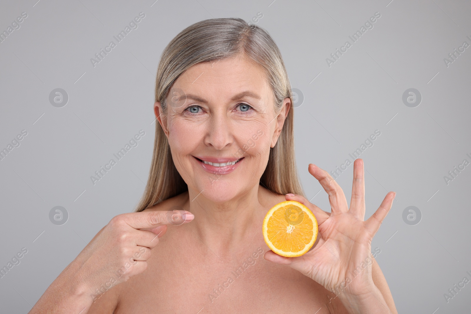 Photo of Beautiful woman with half of orange rich in vitamin C on grey background