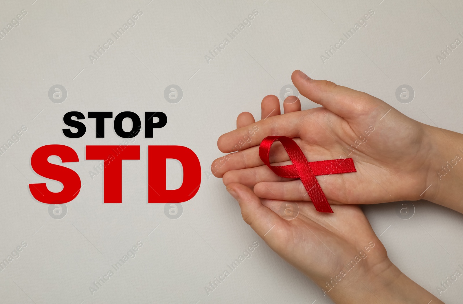 Image of Young woman holding red awareness ribbon on beige background, top view. Stop STD 