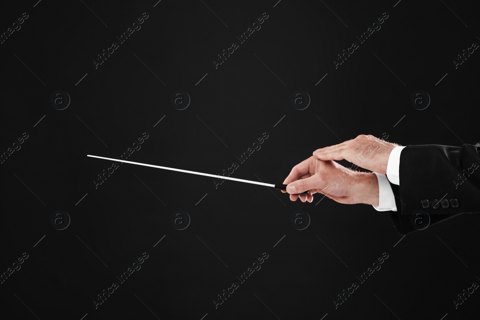 Photo of Professional conductor with baton on black background, closeup