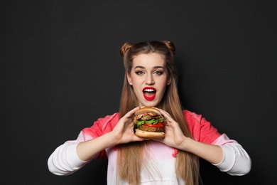 Photo of Pretty woman with tasty burger on black background