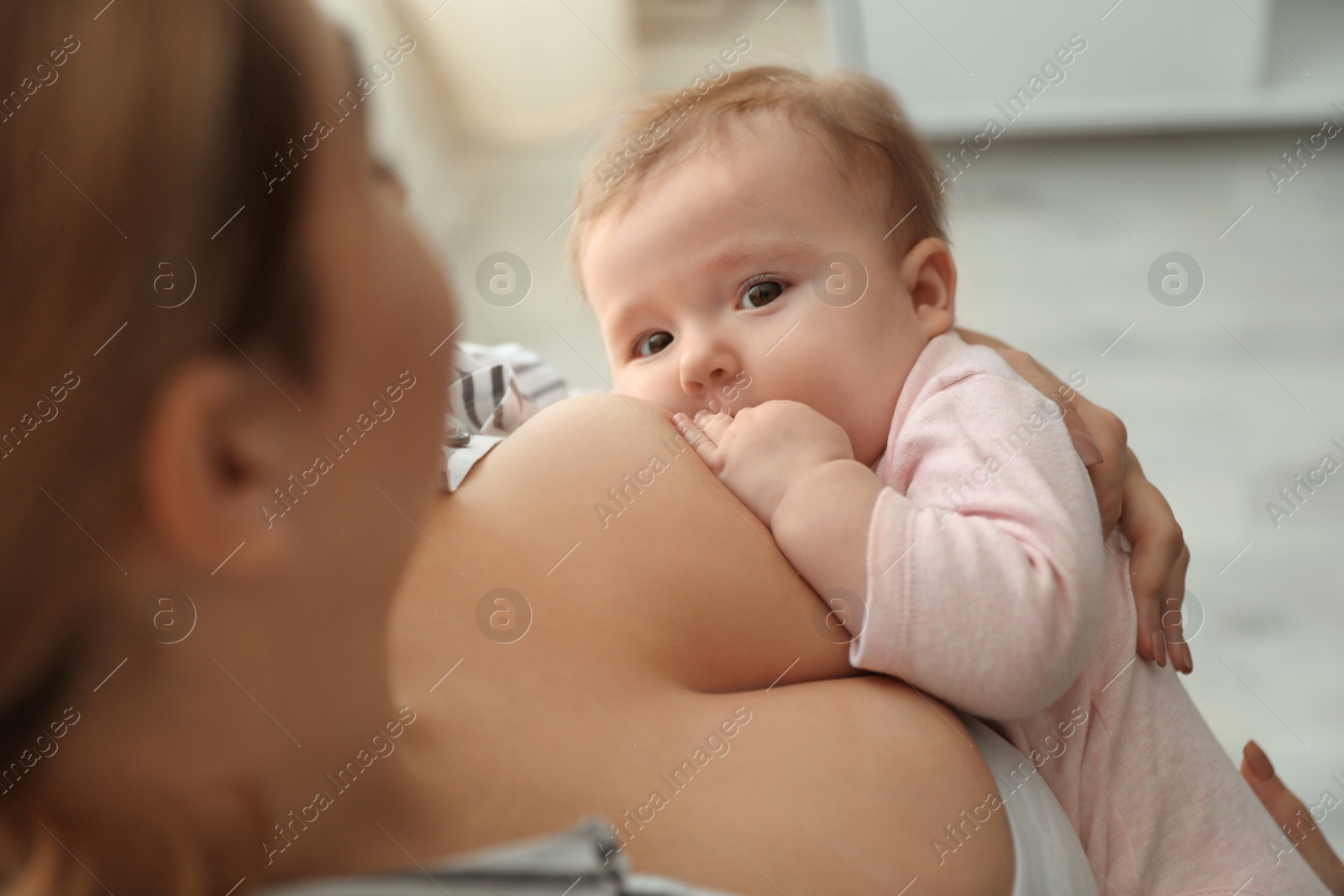 Photo of Young woman breastfeeding her baby at home, closeup