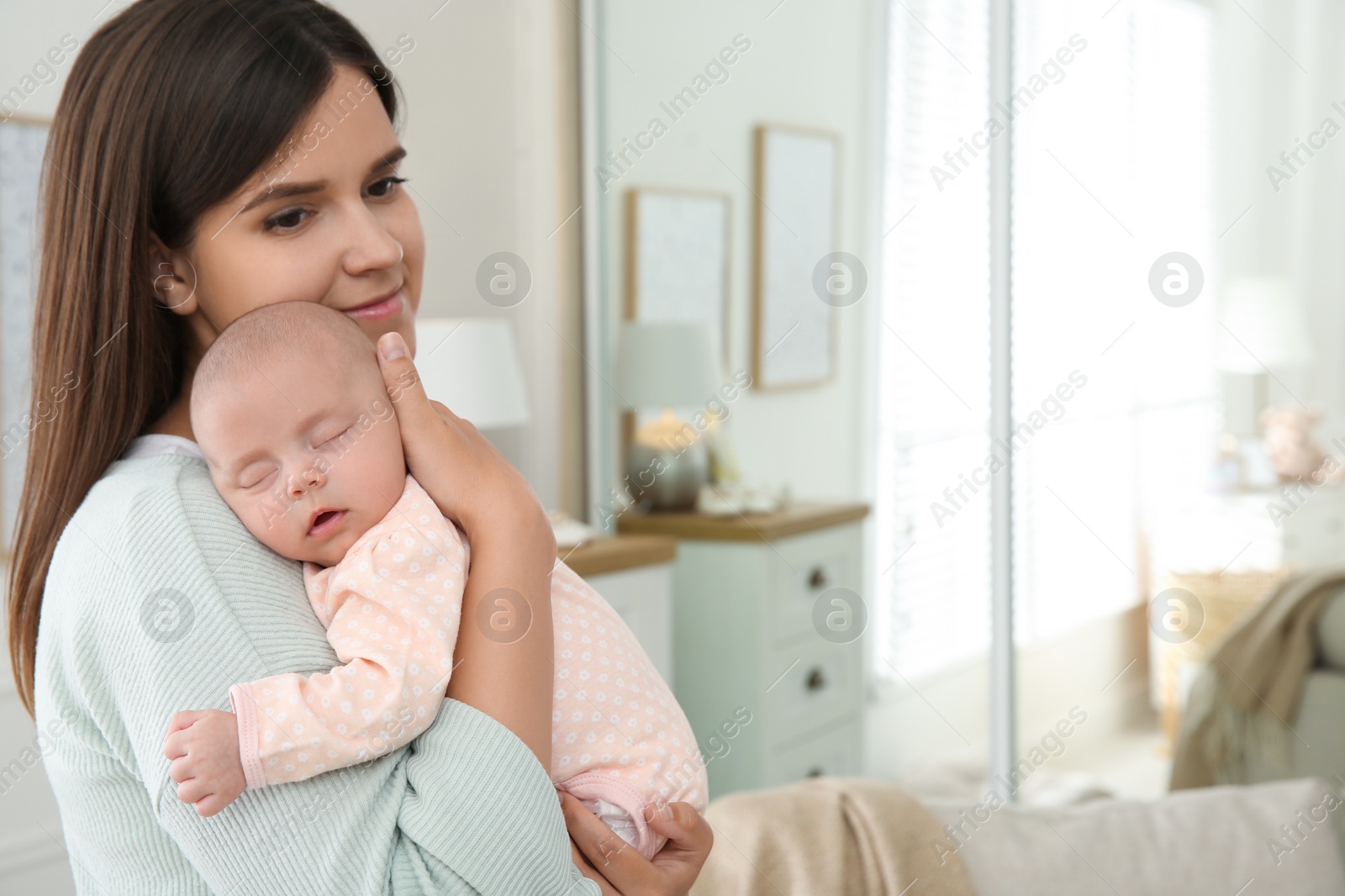 Photo of Mother holding her sleeping baby at home