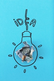 Photo of Composition with crumpled banknote, drawing of lamp bulb and word IDEA on color background. Creative concept