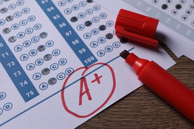 School grade. Answer sheet with red letter A, plus symbol and marker on wooden table, closeup