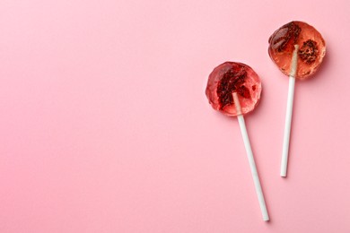 Photo of Sweet colorful lollipops with berries on pink background, flat lay. Space for text