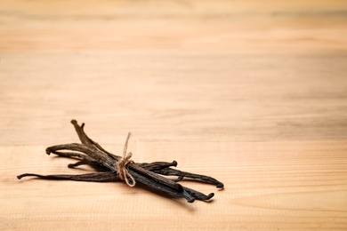 Photo of Aromatic vanilla sticks on wooden background