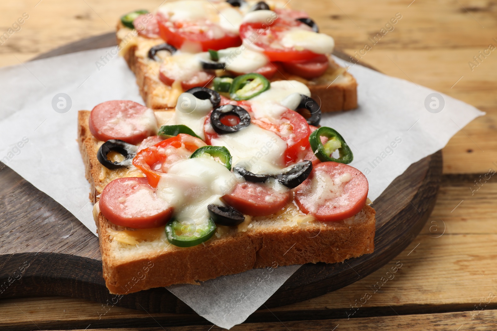 Photo of Tasty pizza toasts on wooden table, closeup