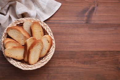 Photo of Hard chuck crackers in wicker basket on wooden table, top view. Space for text