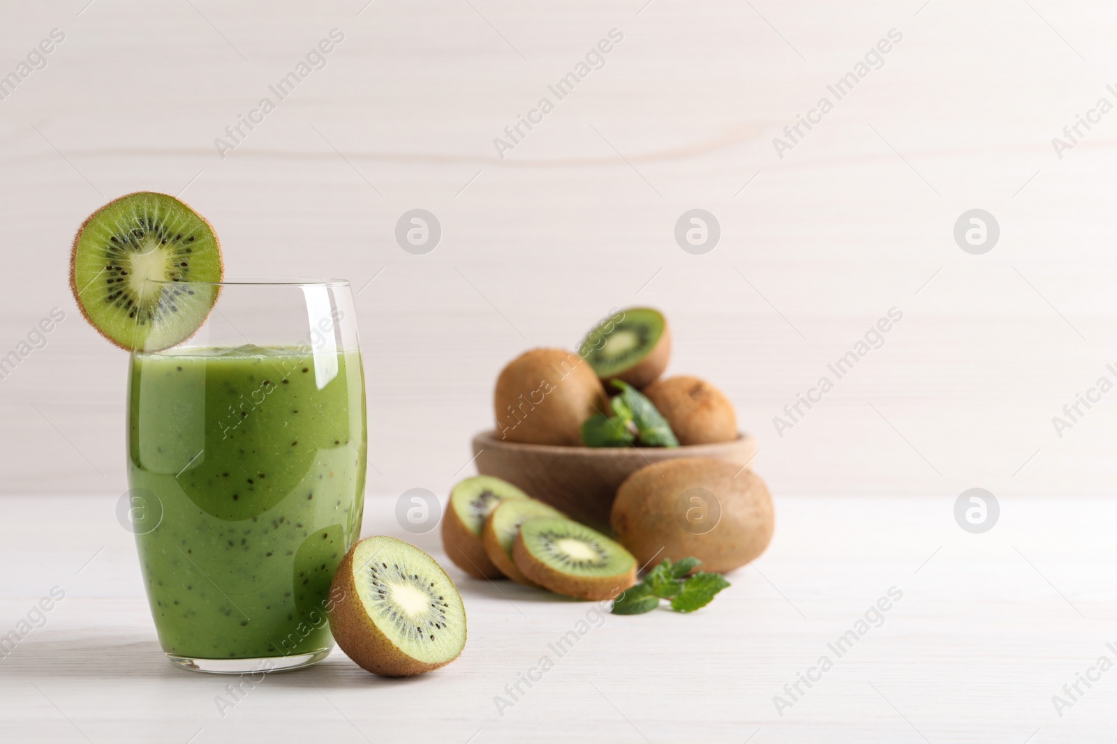 Photo of Delicious kiwi smoothie and fresh fruits on white wooden table