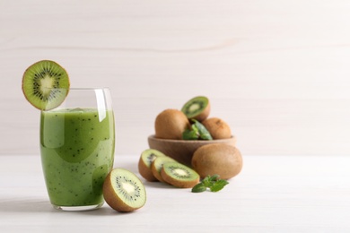 Photo of Delicious kiwi smoothie and fresh fruits on white wooden table