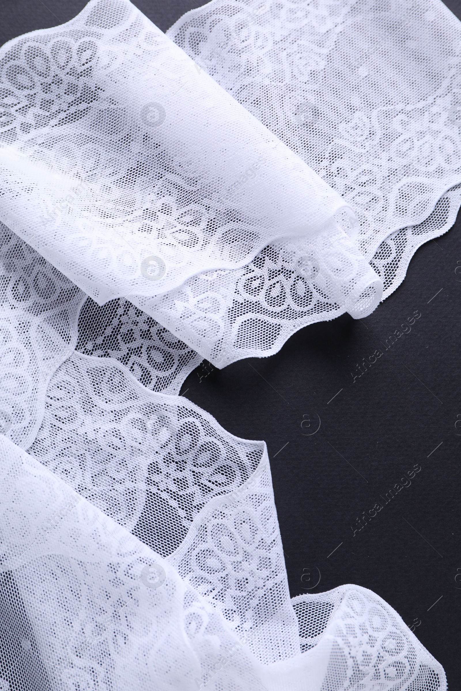 Photo of White lace on black background, top view