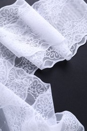 Photo of White lace on black background, top view