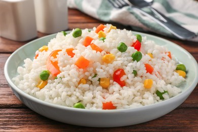 Delicious rice with vegetables on wooden table