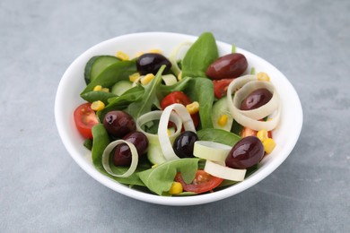 Bowl of tasty salad with leek and olives on grey table, closeup