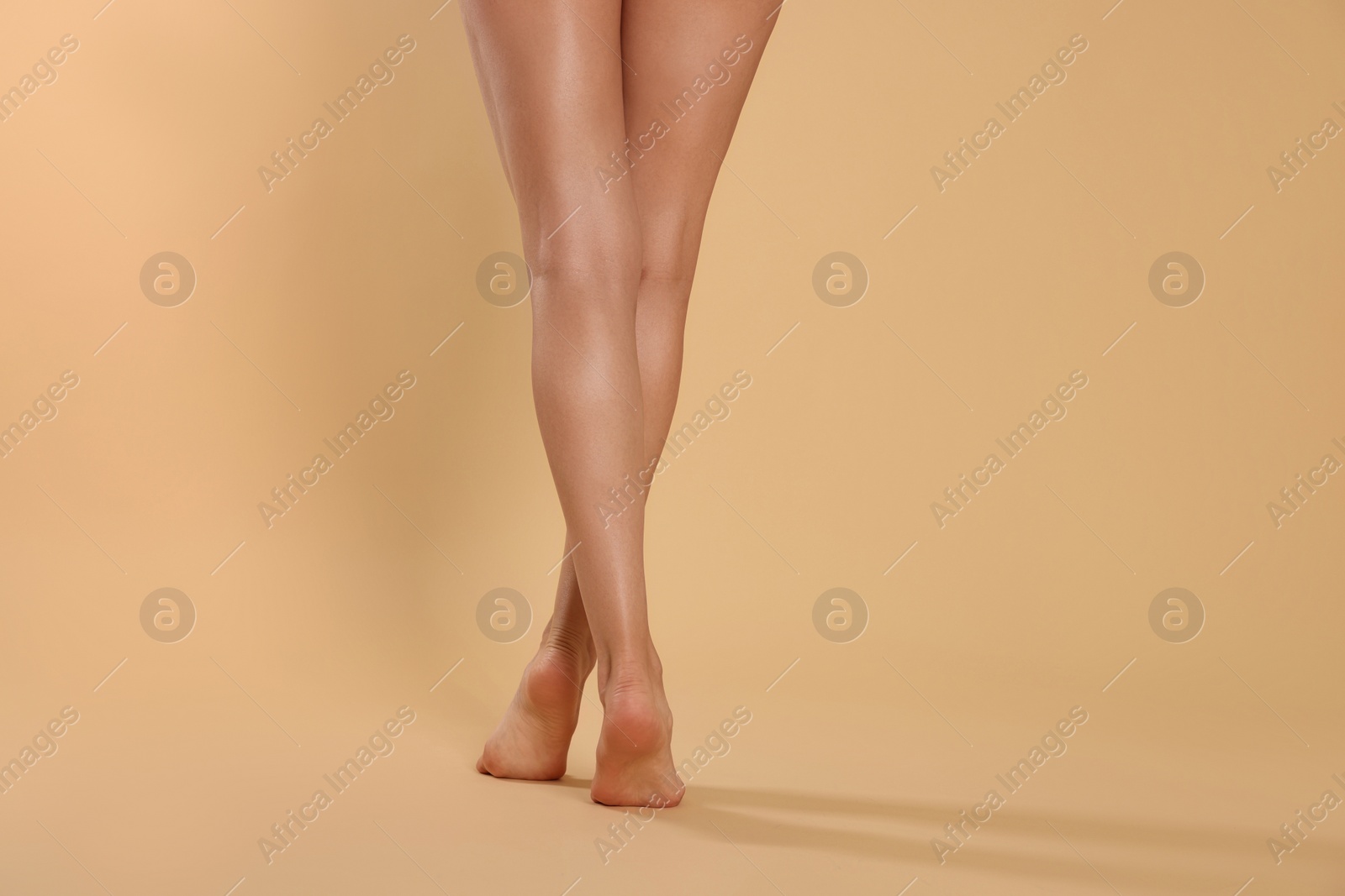 Photo of Woman with beautiful long legs on beige background, closeup