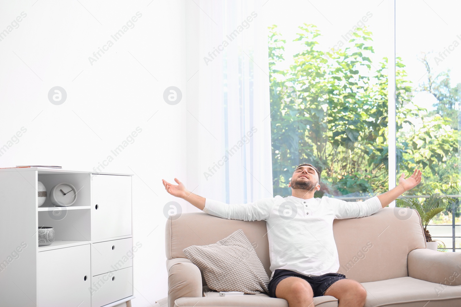 Photo of Young man relaxing under air conditioner at home