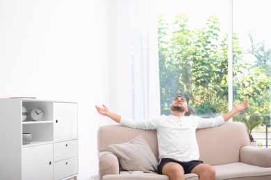 Young man relaxing under air conditioner at home