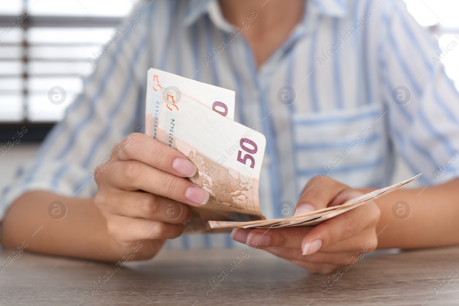 Photo of Woman with Euro banknotes at wooden table indoors, closeup