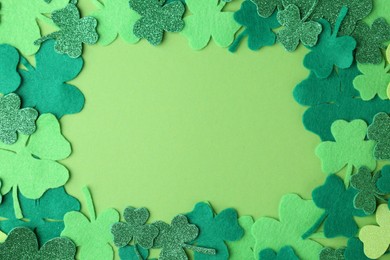 Photo of St. Patrick's day. Frame of decorative clover leaves on green background, top view. Space for text