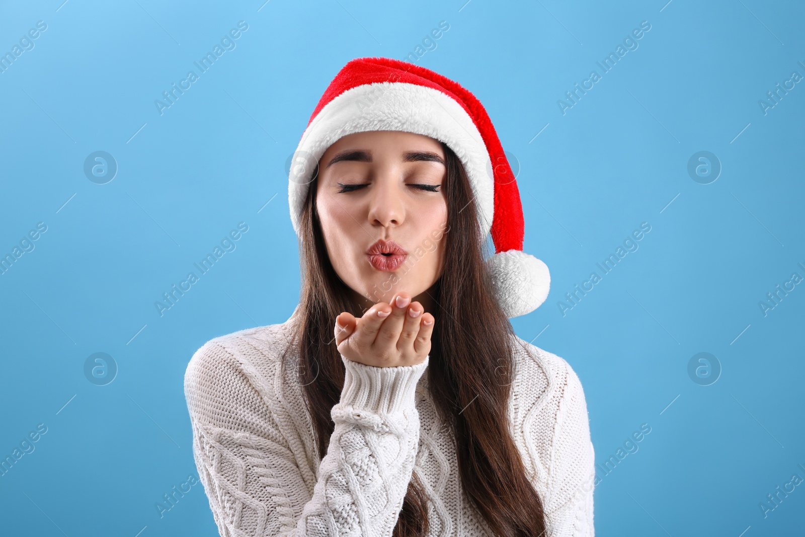 Photo of Beautiful woman wearing Santa Claus hat on light blue background