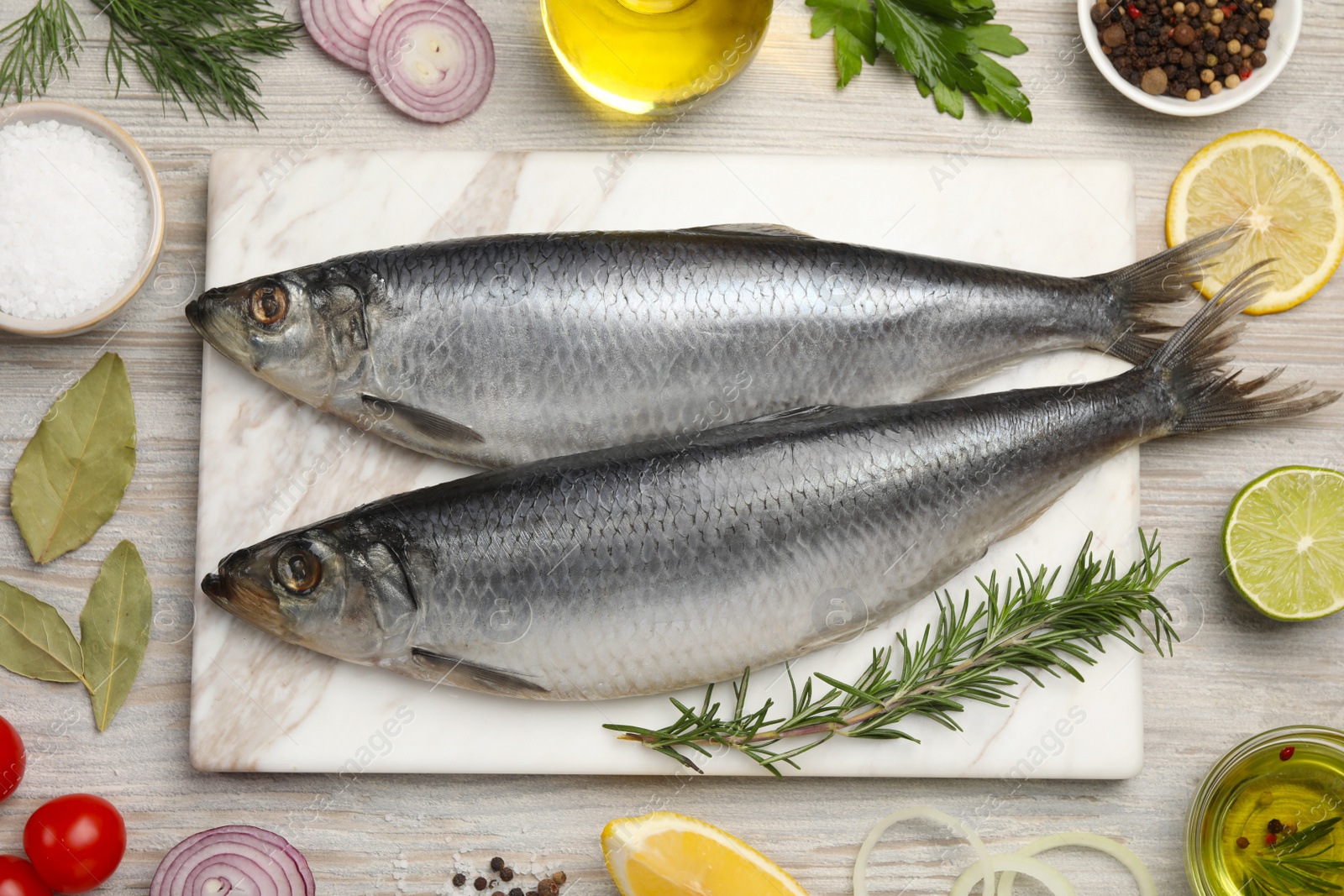 Photo of Delicious salted herrings and different ingredients on light wooden table, flat lay