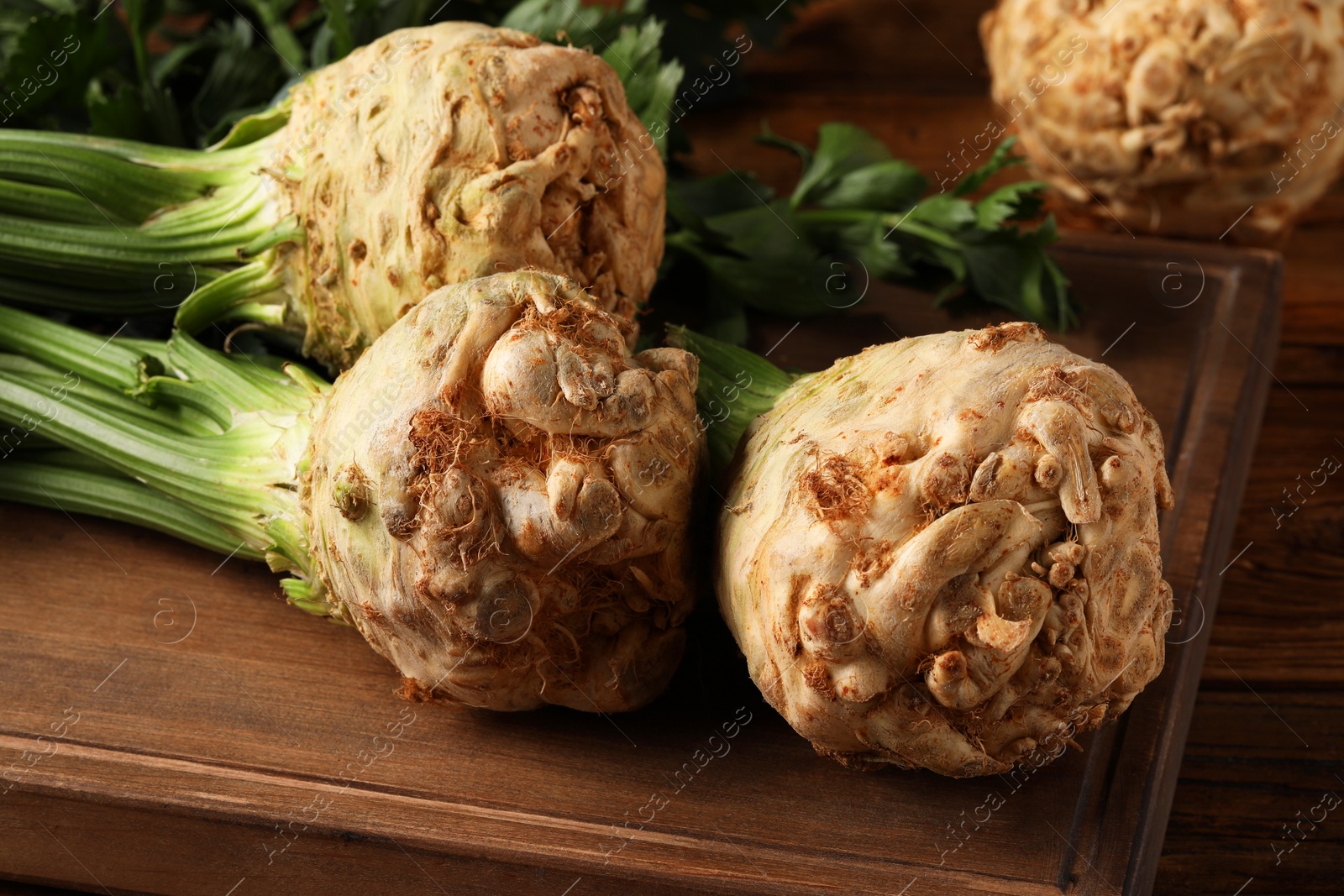 Photo of Fresh raw celery roots on wooden table, closeup