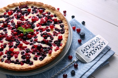 Delicious currant pie and fresh berries on white wooden table