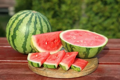 Delicious cut and whole ripe watermelons on wooden table outdoors