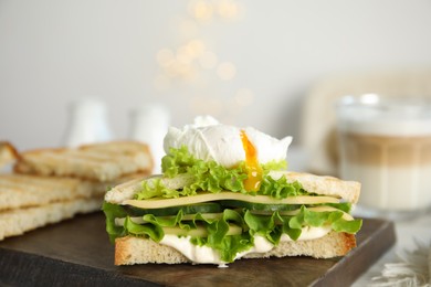 Photo of Delicious sandwich with vegetables and poached egg on board, closeup