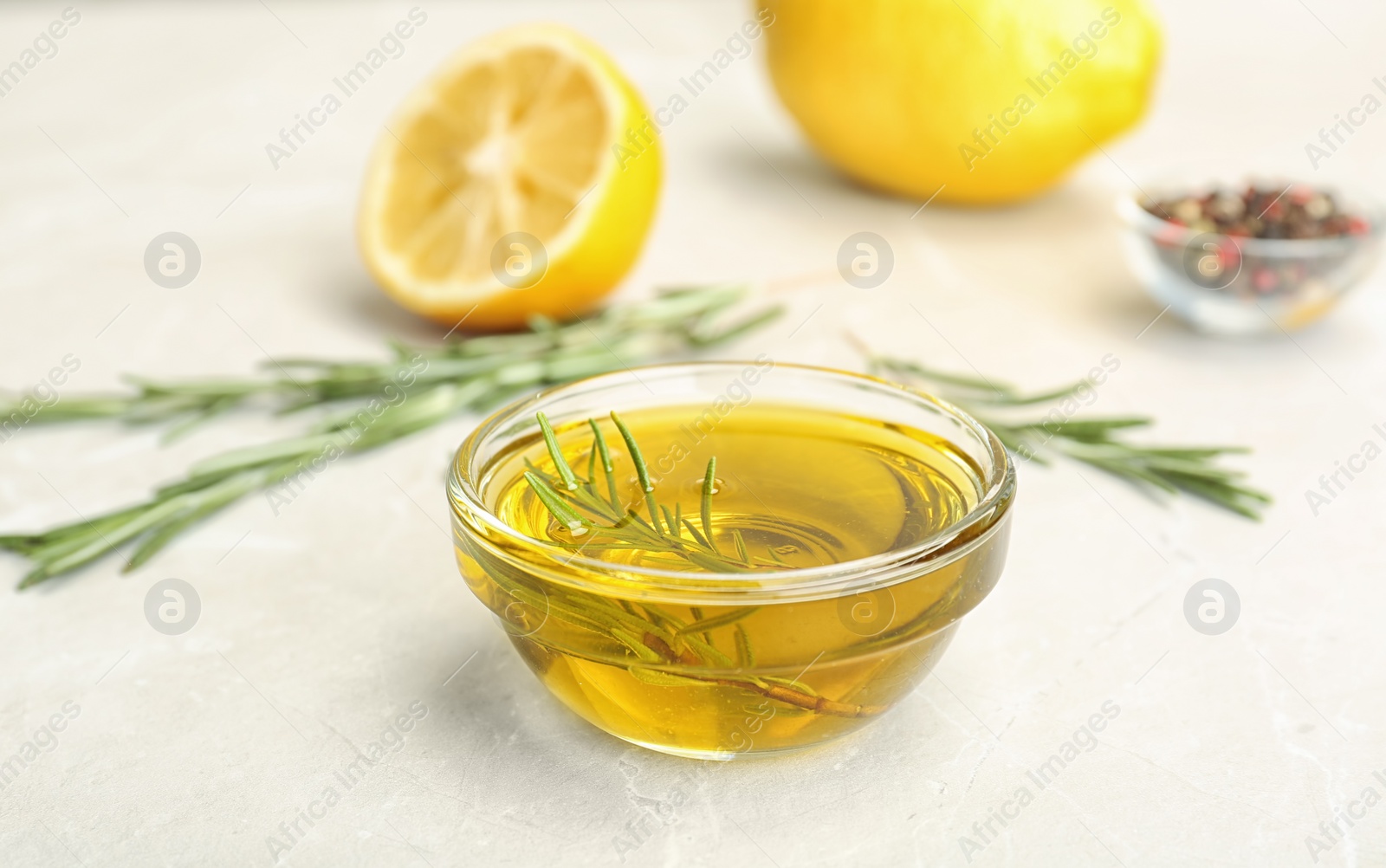 Photo of Bowl with essential rosemary oil on table