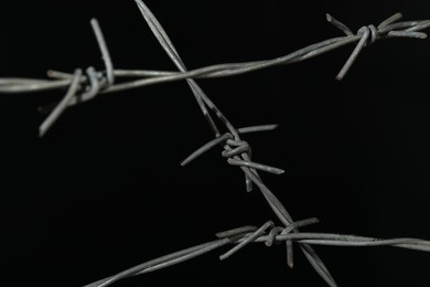 Photo of Metal barbed wire on black background, closeup