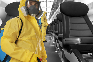 Image of People wearing protective suits cleaning cabin in airplane to prevent spreading of Coronavirus