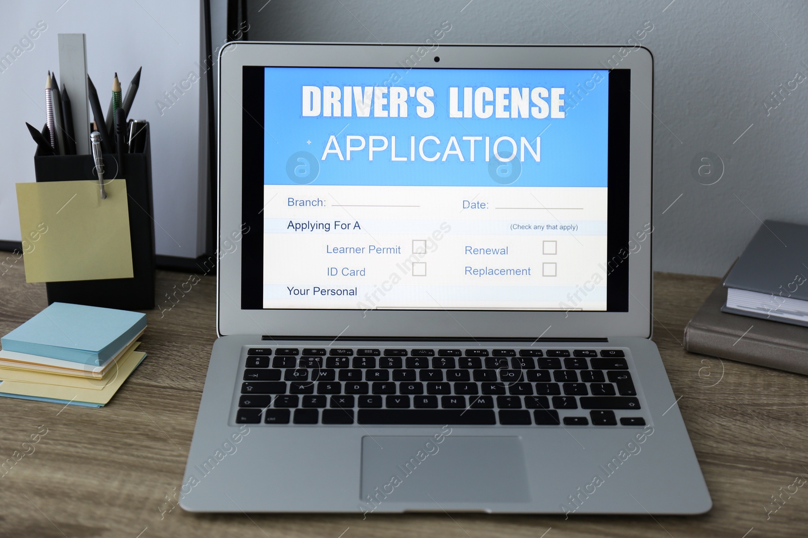 Photo of Laptop with driver's license application form on table in office