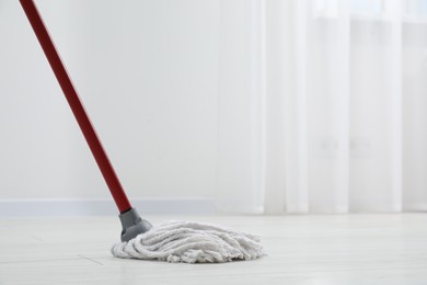 Photo of Cleaning dirty parquet floor with mop indoors. Space for text