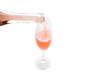 Pouring rose champagne from bottle into glass on white background