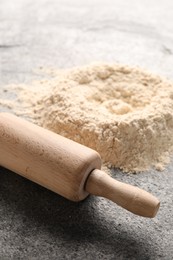 Rolling pin and scattered flour on grey textured table, closeup