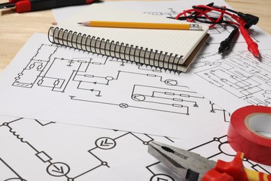 Photo of Wiring diagrams, tools and office stationery on wooden table, closeup