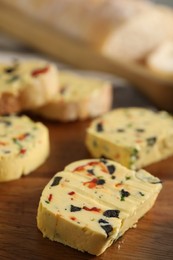 Photo of Tasty butter with olives, chili pepper and parsley on wooden table, closeup