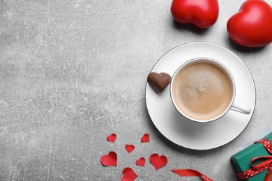 Cup of coffee, chocolate candy and gift box on light grey table, flat lay with space for text. Valentine's day breakfast
