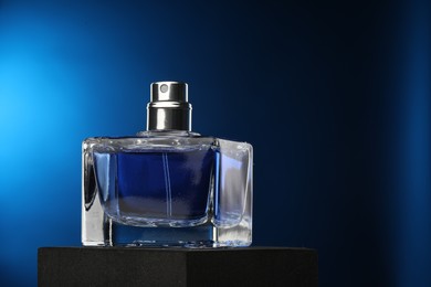 Luxury men`s perfume in bottle against dark blue background, space for text