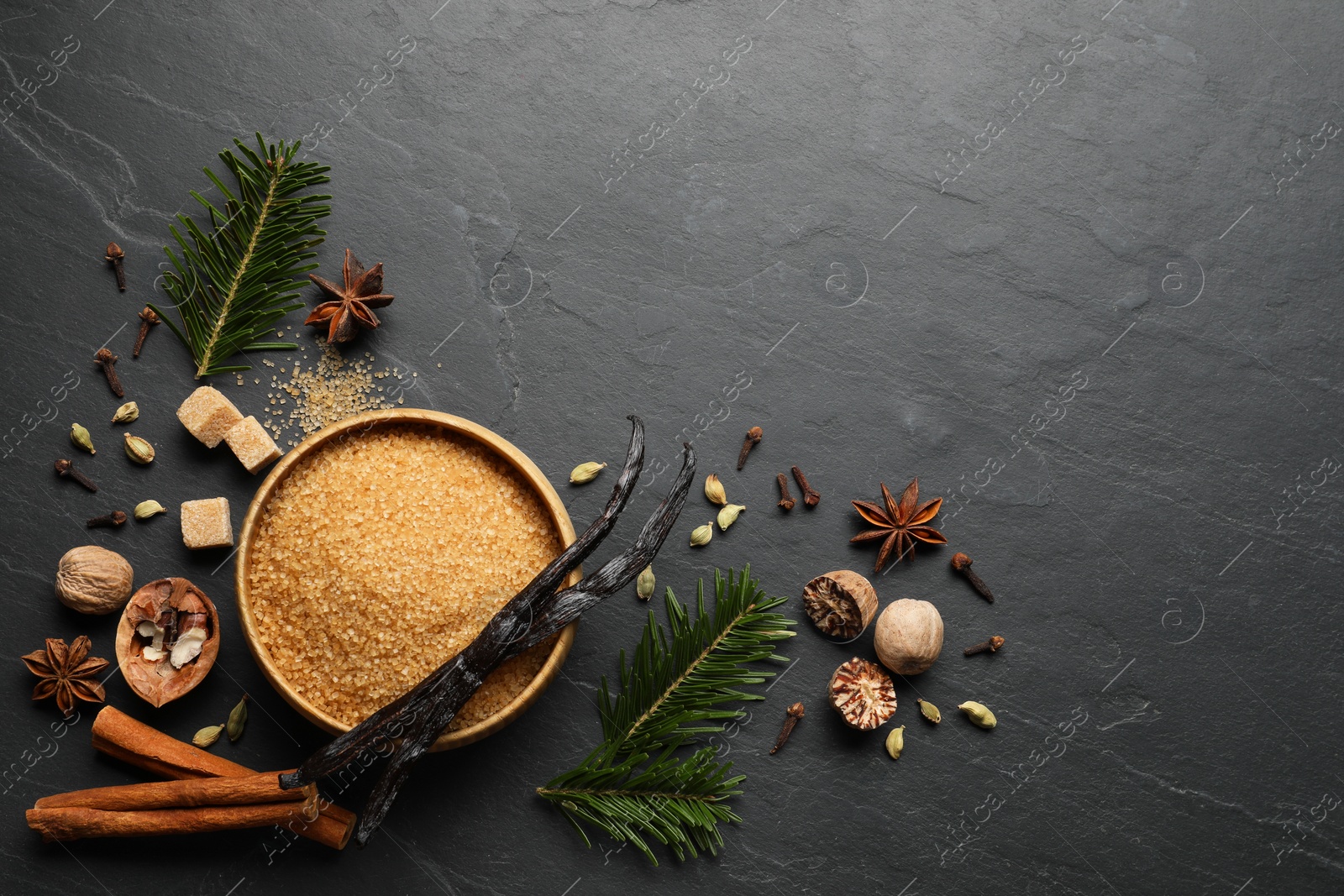 Photo of Different aromatic spices and fir branches on dark textured table, flat lay. Space for text