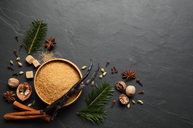 Photo of Different aromatic spices and fir branches on dark textured table, flat lay. Space for text