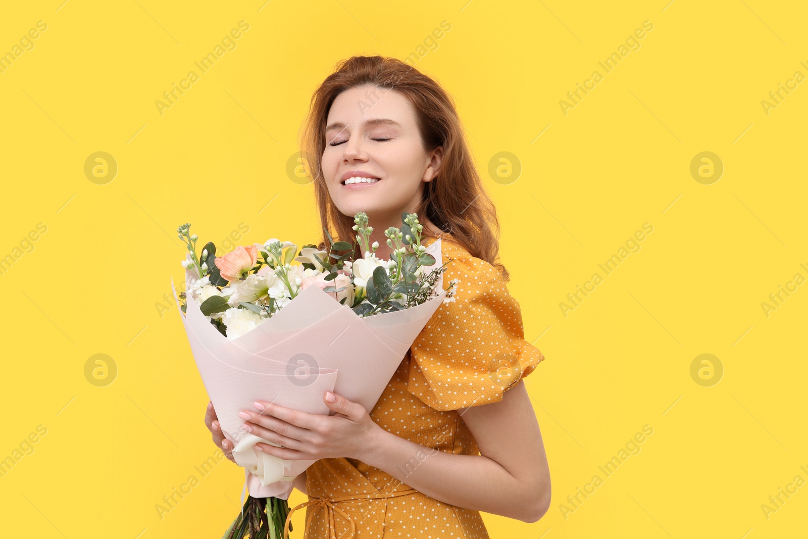 Photo of Happy woman with bouquet of beautiful flowers on yellow background