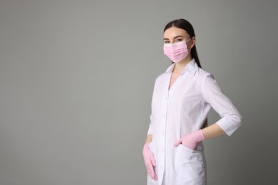 Cosmetologist in medical uniform on grey background, space for text