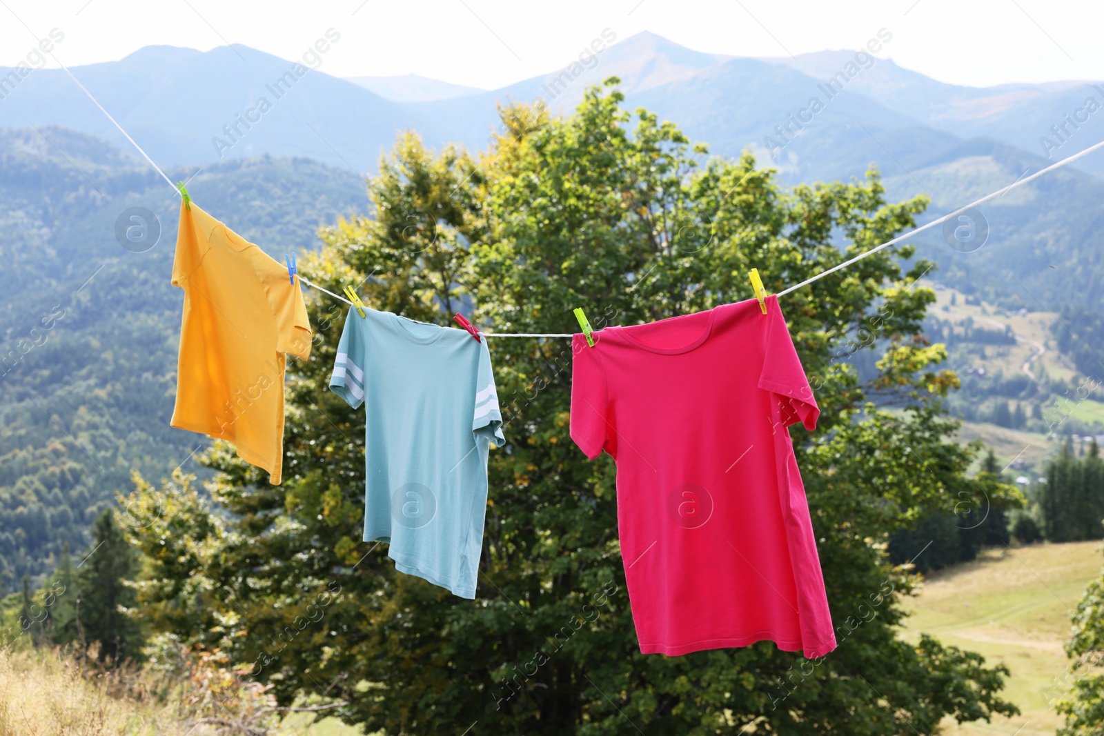 Photo of Washing line with clean laundry and clothespins in mountains