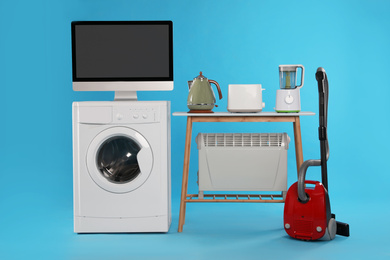 Photo of Set of different home appliances with vacuum cleaner on light blue background