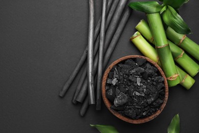 Photo of Fresh bamboo and charcoal on black background, flat lay. Space for text