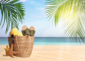 Image of Bag with accessories on sunny ocean beach, space for text. Summer vacation